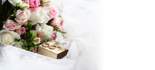 Elegant wedding accessories of an attractive bride. Wedding rings, shoes, bridal bouquet, floral arrangements, veil. Copy space for text. Background for greeting card or invitation.
