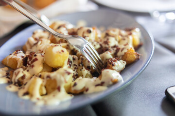 portion of fried potatoes with white sauce and bacon
