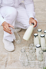 Unrecognizable modern milkman delivering milk and bringing back empty glass bottles, vertical high angle shot