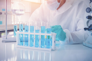 Asian Scientist working on blue test tube to analysis and develop vaccine of covid-19 virus in lab...