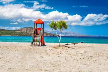 View of the deserted sandy beach with single tree and an empty playground with slide and seesaw or...