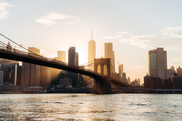 Wide angle view on Manhattan and Brooklyn bridge skyline with sunset and sun flare. World Trade...