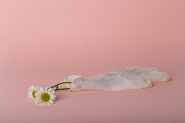 Daisies in a rubber glove on pink background. Earth day concept 