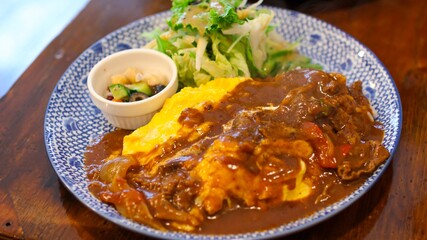 Hayashi rice (Hashed beef rice) on an omelette that is filled with fried rice (Omu Hayashi), salad and pickles in a Japanese restaurant