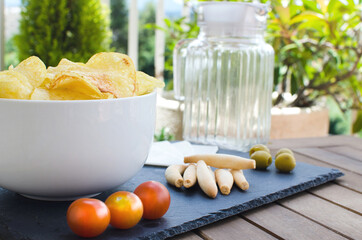 appetizer and snack with potatoes, cheese, tomatoes, olives and bread on a slate base on a wooden table