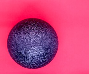 Black fascia ball on a red background from above. Massage ball made of polystyrene for fascial release