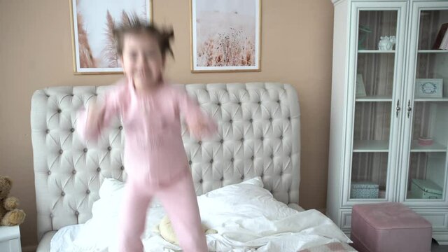 Portrait of girl jumping on a bed, have fun and laughing