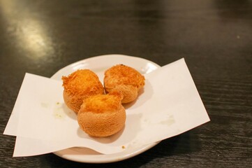 Japanese food, Curry bread (fried bread with curry inside). 3 pieces are on a small plate on a black table