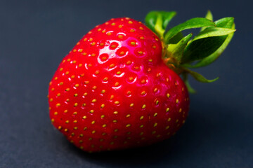 One big strawberry on a dark background.
Close-up.