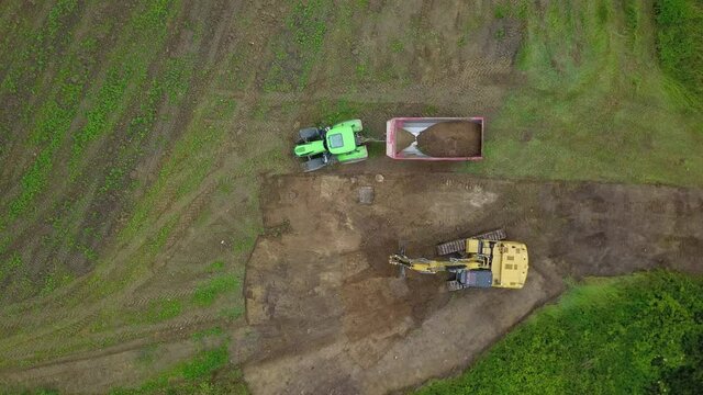 Baustelle: Bagger verl&auml;dt Bodenaushub / Erde in Traktor mit Muldenkipper, Tiefbau, Erdbau, Stra&szlig;enbau