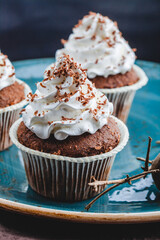 Chocolate cupcake with white cream on a blue plate close-up. Traditional French dessert