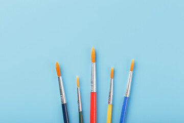 Brushes of different colors for drawing, creativity and art on a blue background.