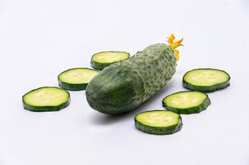 Fresh tasty wholesome cucumber and cut slices lie on a white background.