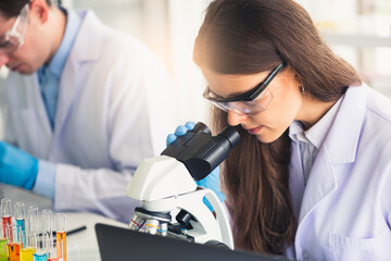 female scientist looking through a microscope