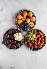 A top down view of three trays filled with tasty complimentary fruit in complimentary colours.