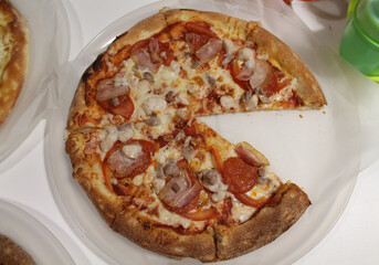 Hot pizza with meat, tomatoes and cheese, cooked in the oven. The concept of cooking delicious food at home.
