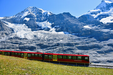 Beautiful scenery with cogwheel red train of the famous Jungfrau Railway from Jungfraujoch ( Top of Europe) to Kleine Scheidegg, Bernese Oberland, Switzerland
