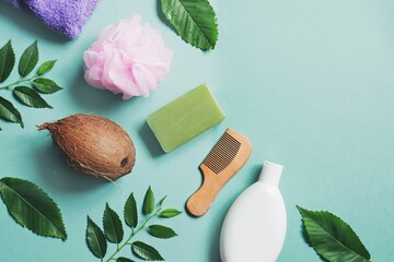 Organic bio cosmetic products on a green background. Natural coconut shampoo, wooden comb, pink...