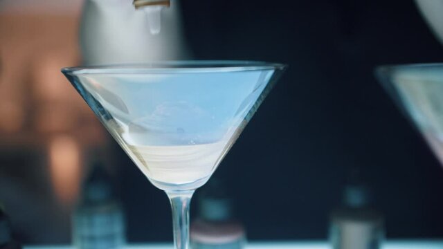 Hair salon colorist mixing dye in fancy martini glass with customer watching. Modern marketing ploy in beauty shop. Cosmetology and small business operation of beauty shop.