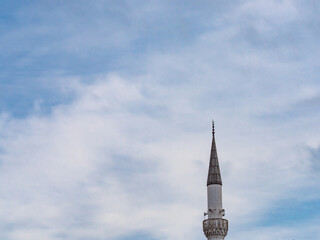 Minaret of a Muslim mosque on the background of the cloudy sky.