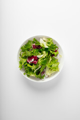 Summer salad in a bowl top view on white table. Minimal style vegetarian dish
