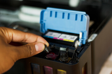 Business man or technician is checking and changing the printer equipment cartridges tone of laser jet multi function printer in the office. Close-up shot of CMYK ink cartridges for laser printer.