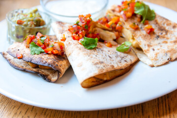 Delicious Mexican quesallidas made with chicken, tomato pieces and served with guacamole sauce.