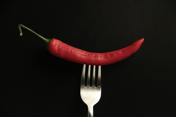 red pepper in a fork on a black background