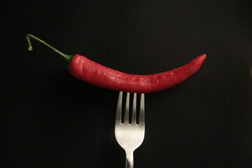 red pepper in a fork on a black background