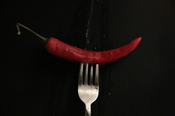 red pepper in a fork on a black background