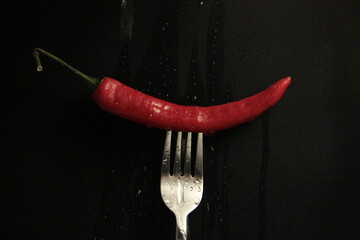 red pepper in a fork on a black background