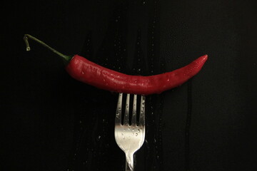 red pepper in a fork on a black background