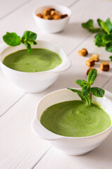 Delicious fresh cream soup of young peas and mint with croutons made of white bread, healthy food