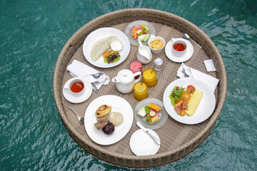Floating breakfast, a large tray in the pool, complete morning meal, with fresh coffee, warm bread, condiments and juices