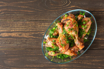 Baked chicken drumsticks with rosemary, spices, onions and dill on a wooden background , top view