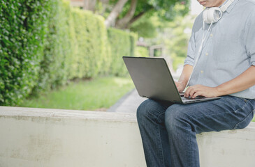 Businessman sitting on the park bench with laptop on his lap.