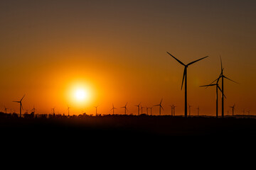 Obraz premium Black Silhouette of windturbines energy generator on amazing sunset at a wind farm in germany