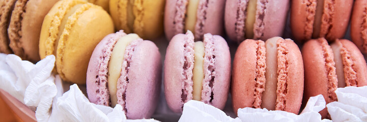 Multi-colored macaroons stacked in a row. Delicious French dessert Macaroon - a small cake or complex cookies made from chopped almonds and meringues. Selective focus. close-up