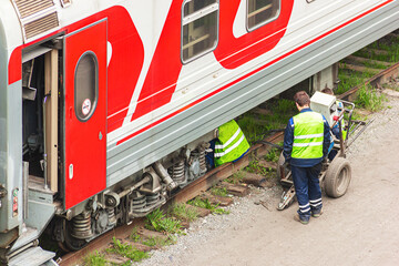 Railway workers repair a railway car.  Passenger wagon is under repair and is serviced by...