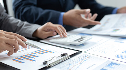 Asian business men and women are brainstorming and analyzing corporate financial graph data in the office.