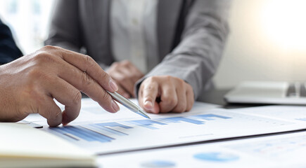 Fototapeta premium Asian business men and women are brainstorming and analyzing corporate financial graph data in the office.