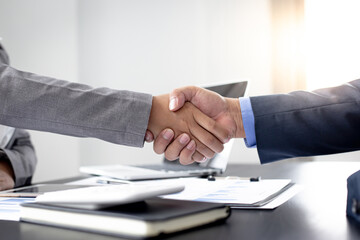 Both businessmen shake hands to congratulate the office of the meeting.