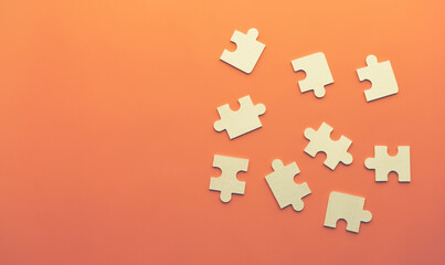 Conceptual image of chaotically lying puzzles with a place under the text on an orange background. Order, Puzzle, Jigsaw Piece, Connection, Leisure Games. The view from the top