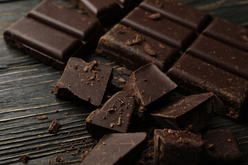 Chocolate pieces on wooden background, close up