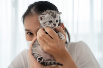 Asian woman wearing mask and holding a cute baby black kitten, Biting fingers