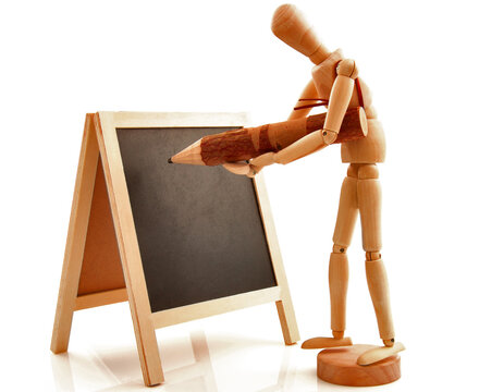 Concept with desk, board, blackboard, chalkboard, frame and wooden toy figure with pencil. Isolated on white background.