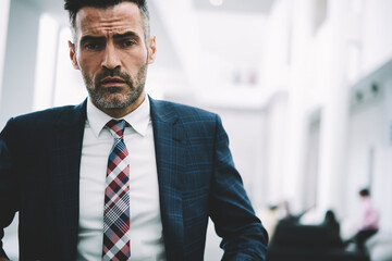 Fototapeta premium Half length portrait of confident proud ceo 50 years old looking at camera.Successful mature businessman dressed in formal wear standing indoors in office interior.Male owner of financial company