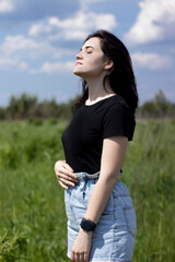 Charming young brunette woman in a black T-shirt and denim shorts. In the country, in the garden. High quality photo