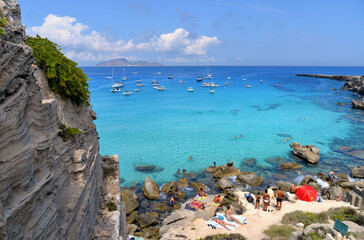 paradise clear torquoise blue water with boats and cloudy blue sky in background in Favignana...