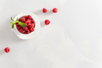 Fresh sweet raspberries in a white cup on white background. Top view, copy space. Natural cosmetics, food background. Summer snack. Banner, poster